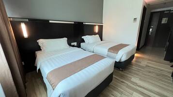 A hotel room with two beds, a dark headboard, and a wooden floor.