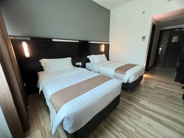 A hotel room with two beds, a dark headboard, and a wooden floor.