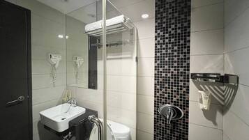 A modern bathroom with a glass-enclosed shower, a white sink, and a black and white tiled wall.