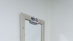 Une salle de bain avec un lavabo blanc, un miroir et un tabouret rond en bois.