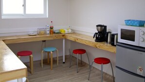Une cuisine compacte dotée d’un plan de travail en bois, d’un four à micro-ondes, d’une machine à café et de quatre tabourets.