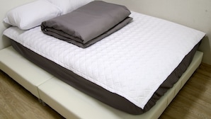 Un lit bien fait, avec une couette blanche et gris foncé, un oreiller blanc et une couverture grise.