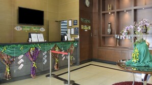 A hotel reception area with a counter, a TV mounted on the wall, a clock, and a decorative plant. - Palette KL Sentral Station Formerly Scott Hotel (Kuala Lumpur)