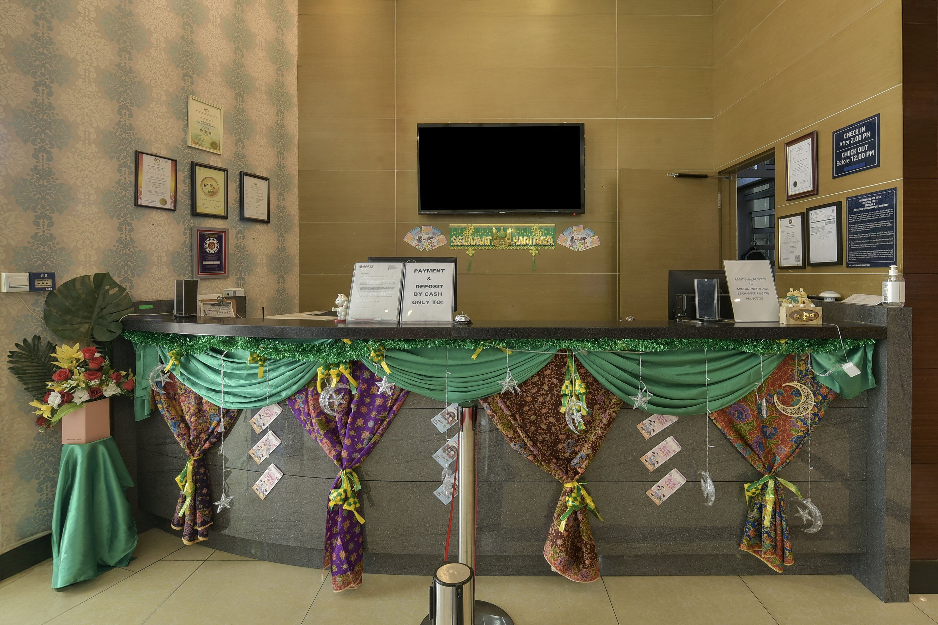 A reception desk with a flat-screen TV, framed certificates, and a green banner.