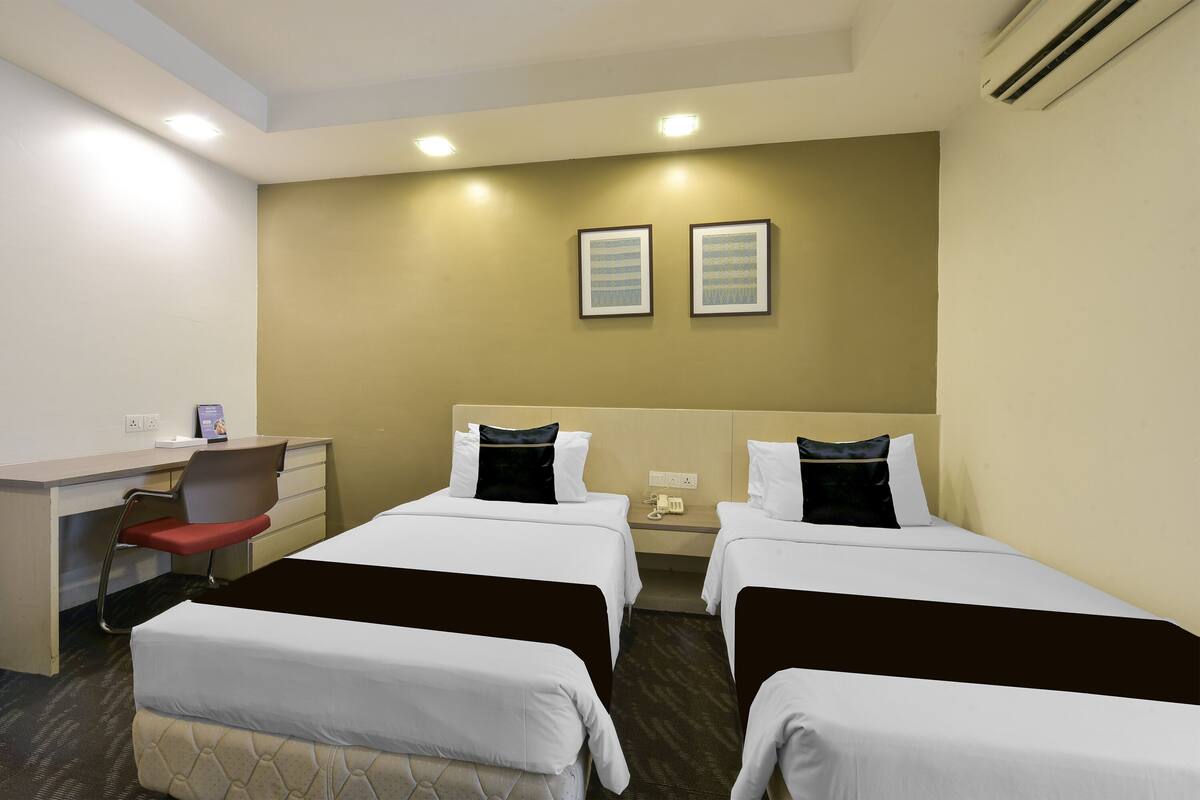 A hotel room with two beds, a desk, a chair, and a small table.