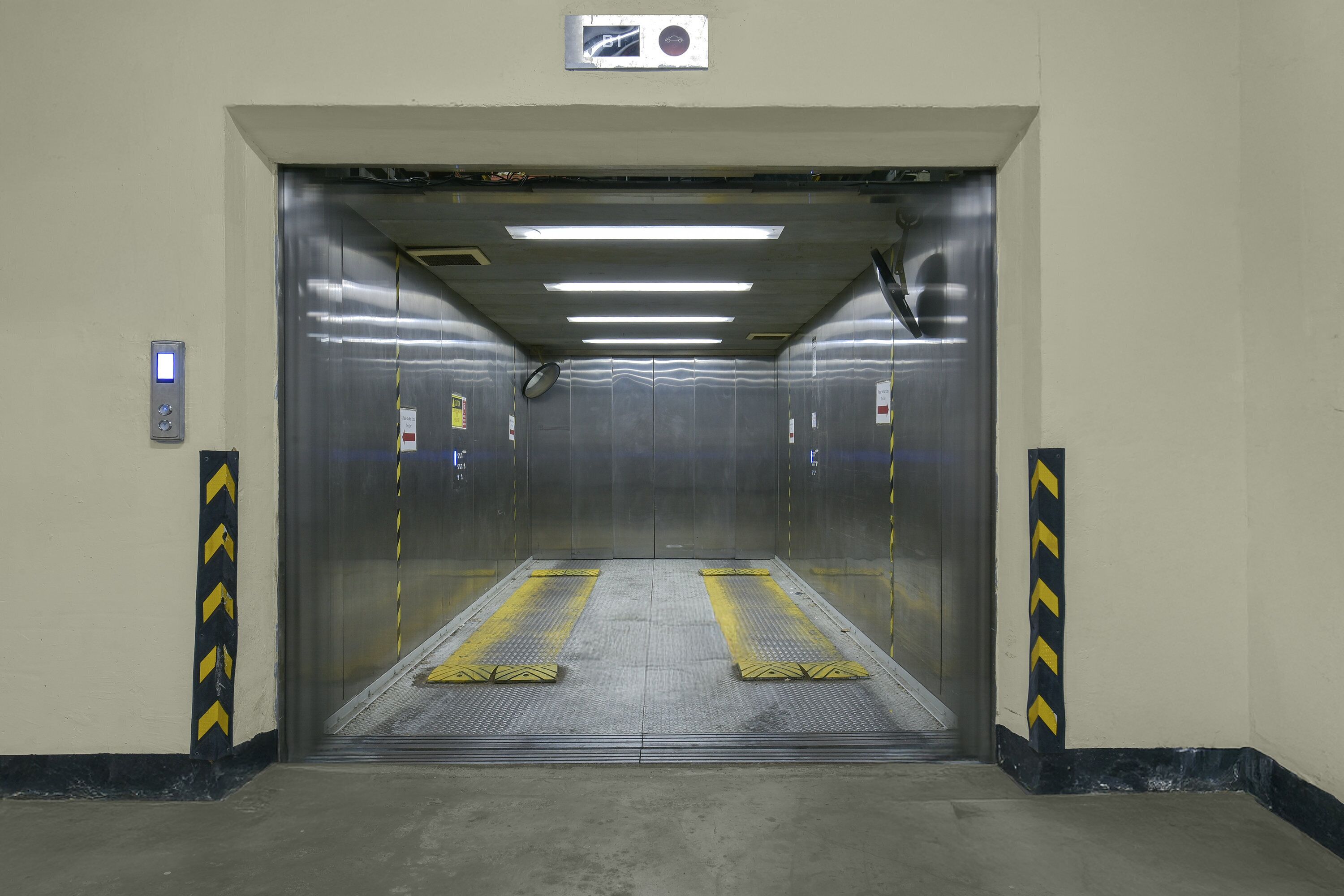 An elevator with a control panel, safety lines, and a sign above the door.