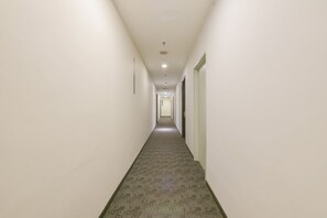 A long, narrow hallway with a carpeted floor and white walls.