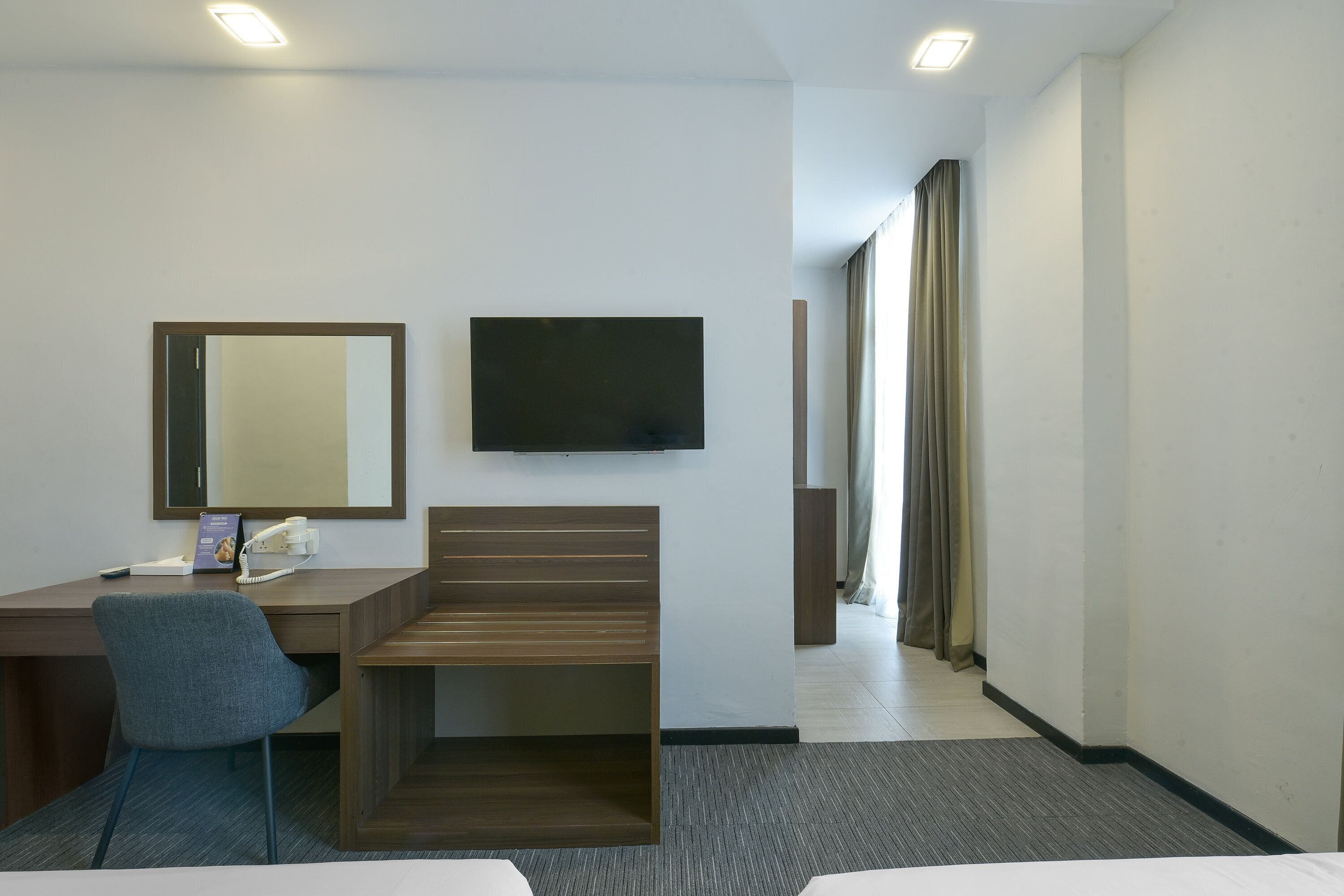 A hotel room with a desk, chair, television, and a bed.