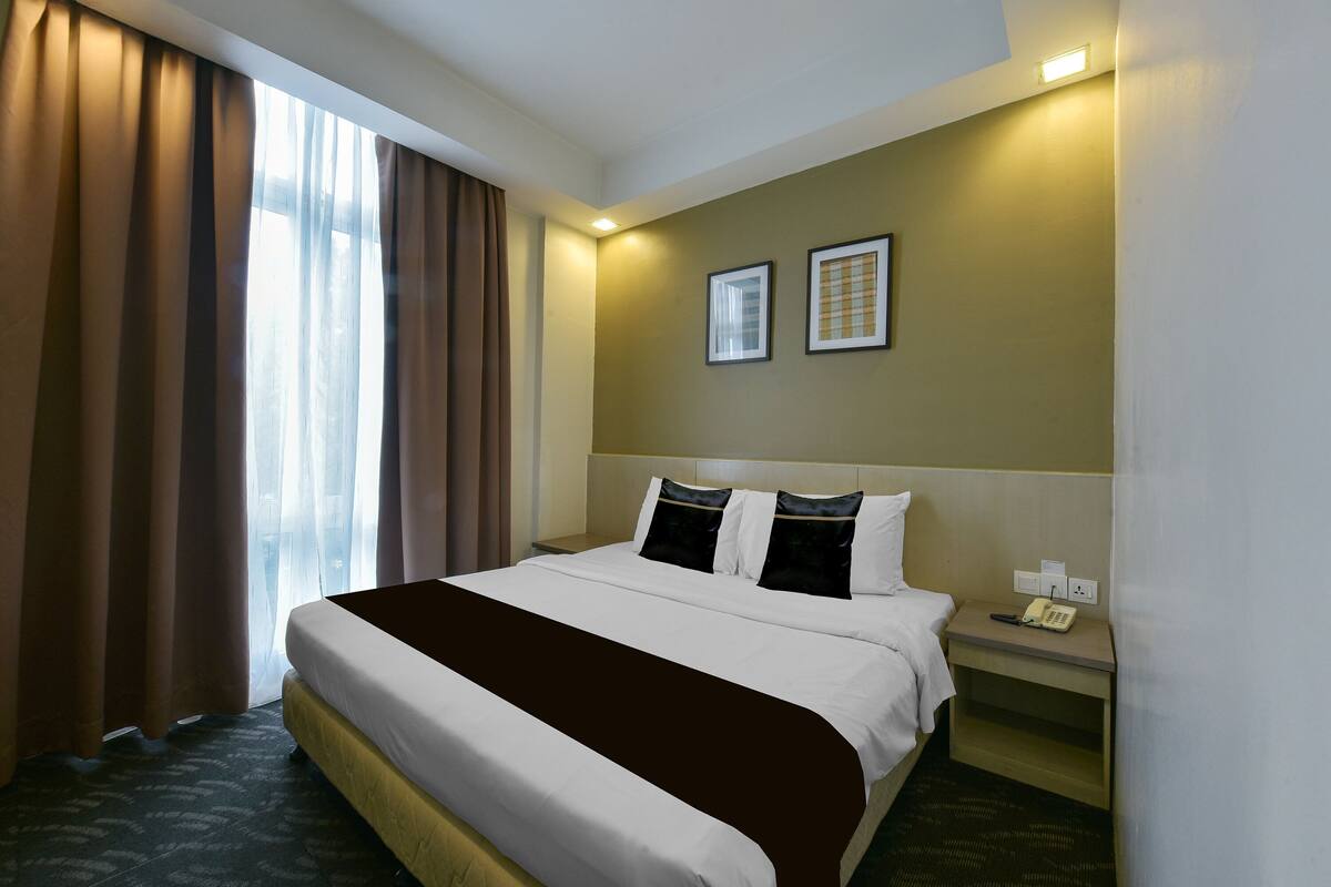 A hotel room with a bed, bedside table, and curtains.