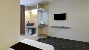 A hotel room with a bed, a television mounted on the wall, a small shelf with a kettle and cups, and a door leading to a bathroom. - Palette KL Sentral Station Formerly Scott Hotel (Kuala Lumpur)
