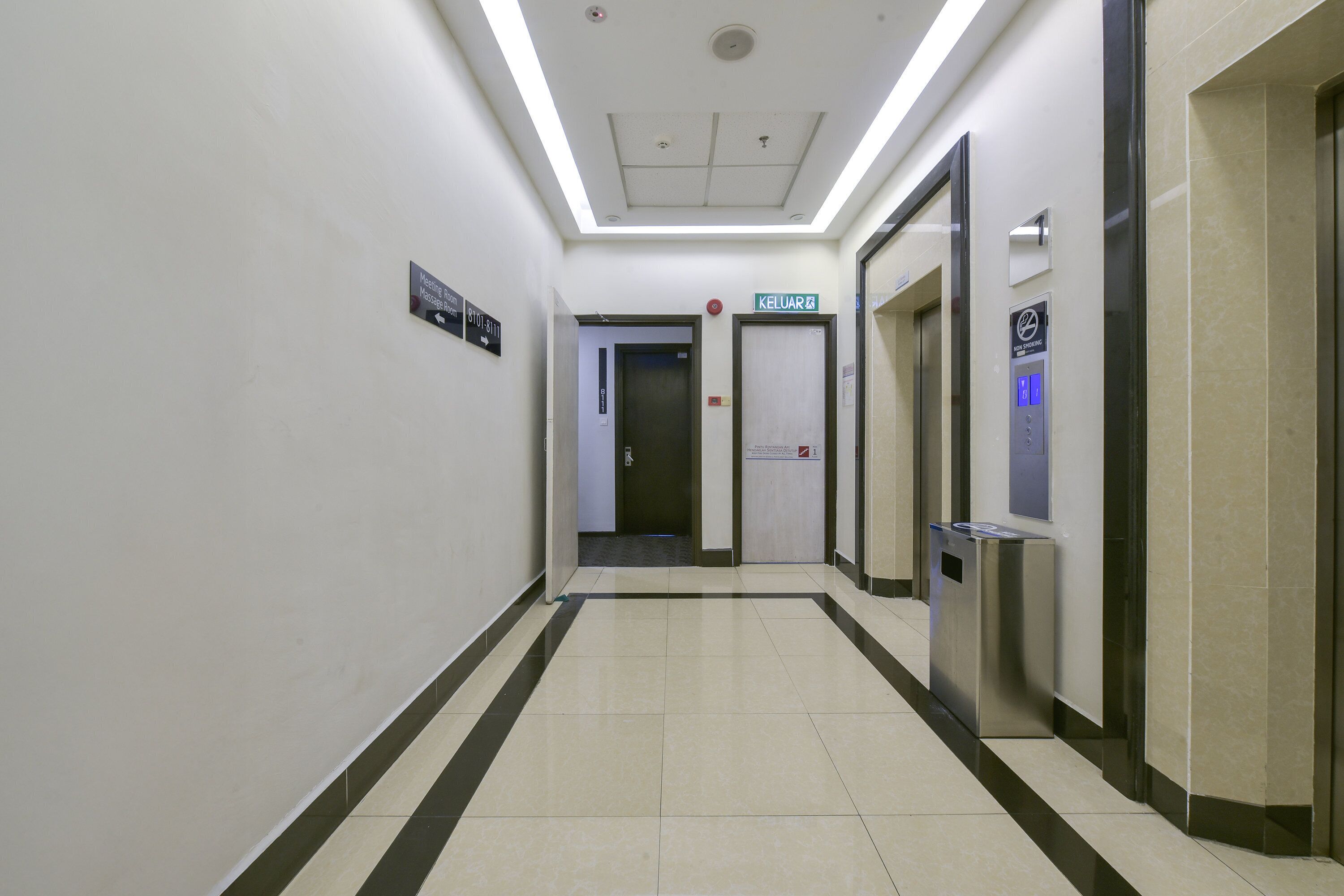 A corridor with a ceiling light, a sign for 'KELUAR 2', and an elevator with a digital display.