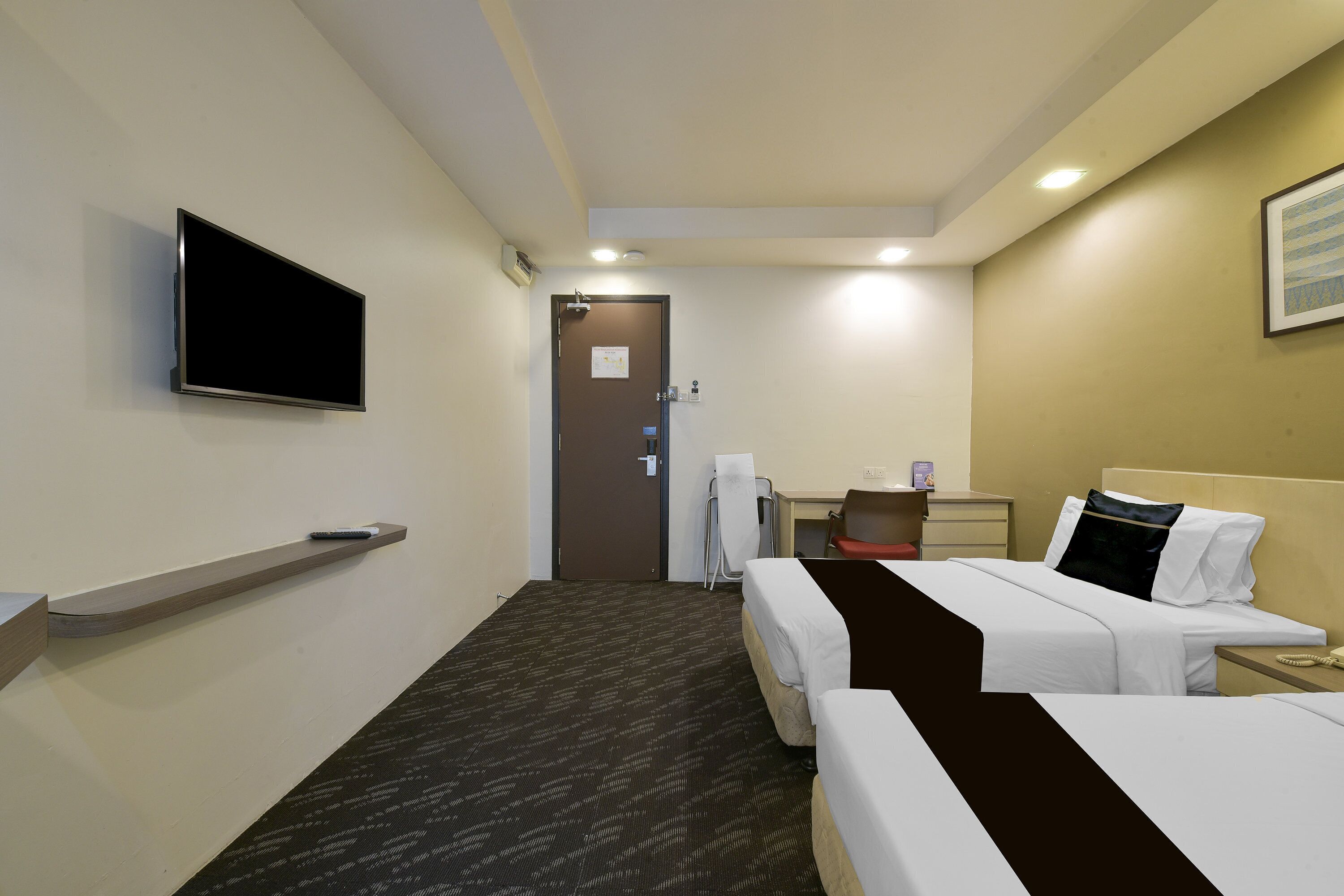 A hotel room with two beds, a TV, a desk, and a chair.