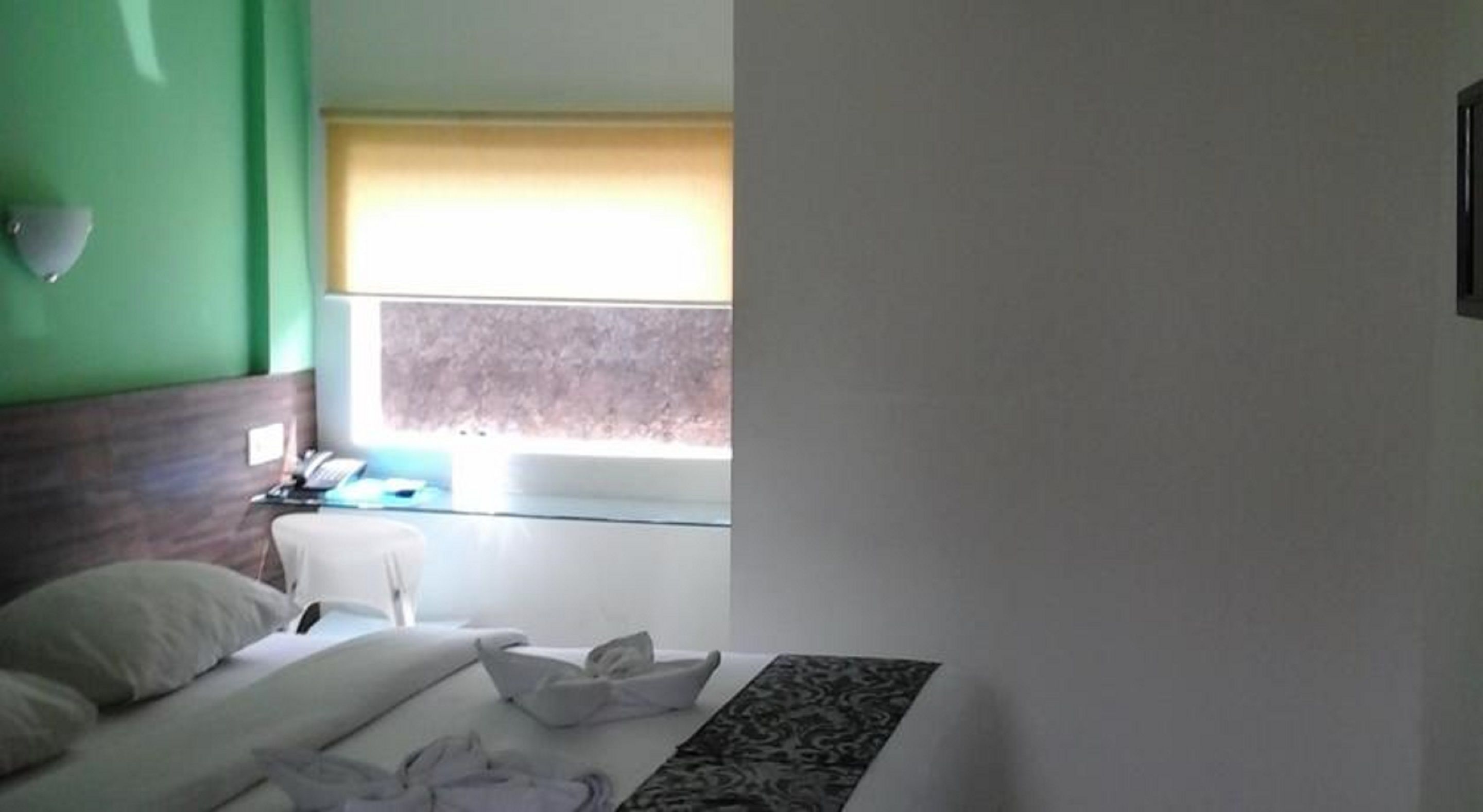 A hotel room with a bed, a desk, and a window with a view.