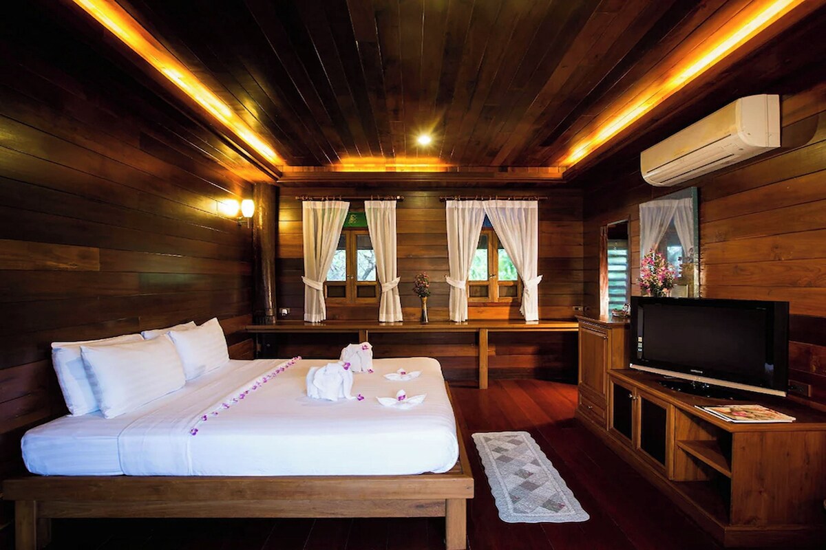 A wooden cabin-style room with a bed, TV, and an air conditioning unit.