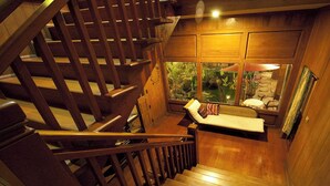 Una escalera de madera que conduce a una habitación con ventana que da a un jardín.