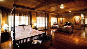 Una cama con dosel en una habitación de madera, con un televisor y una pequeña mesa con lámpara.