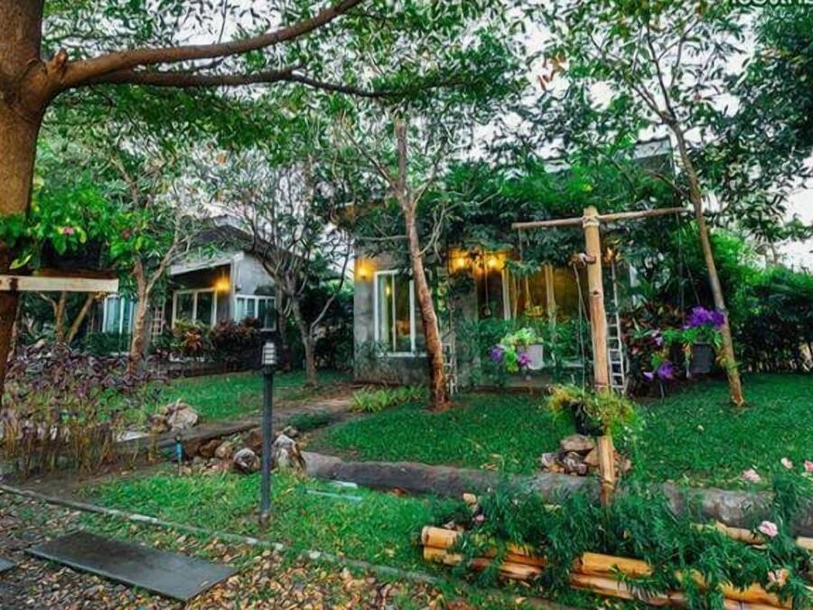 A garden with a swing set, a small house, and a tree.