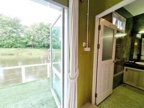 Una stanza con vista sul lago, una porta con pannello in vetro satinato e un bagno con pavimento in piastrelle verdi.