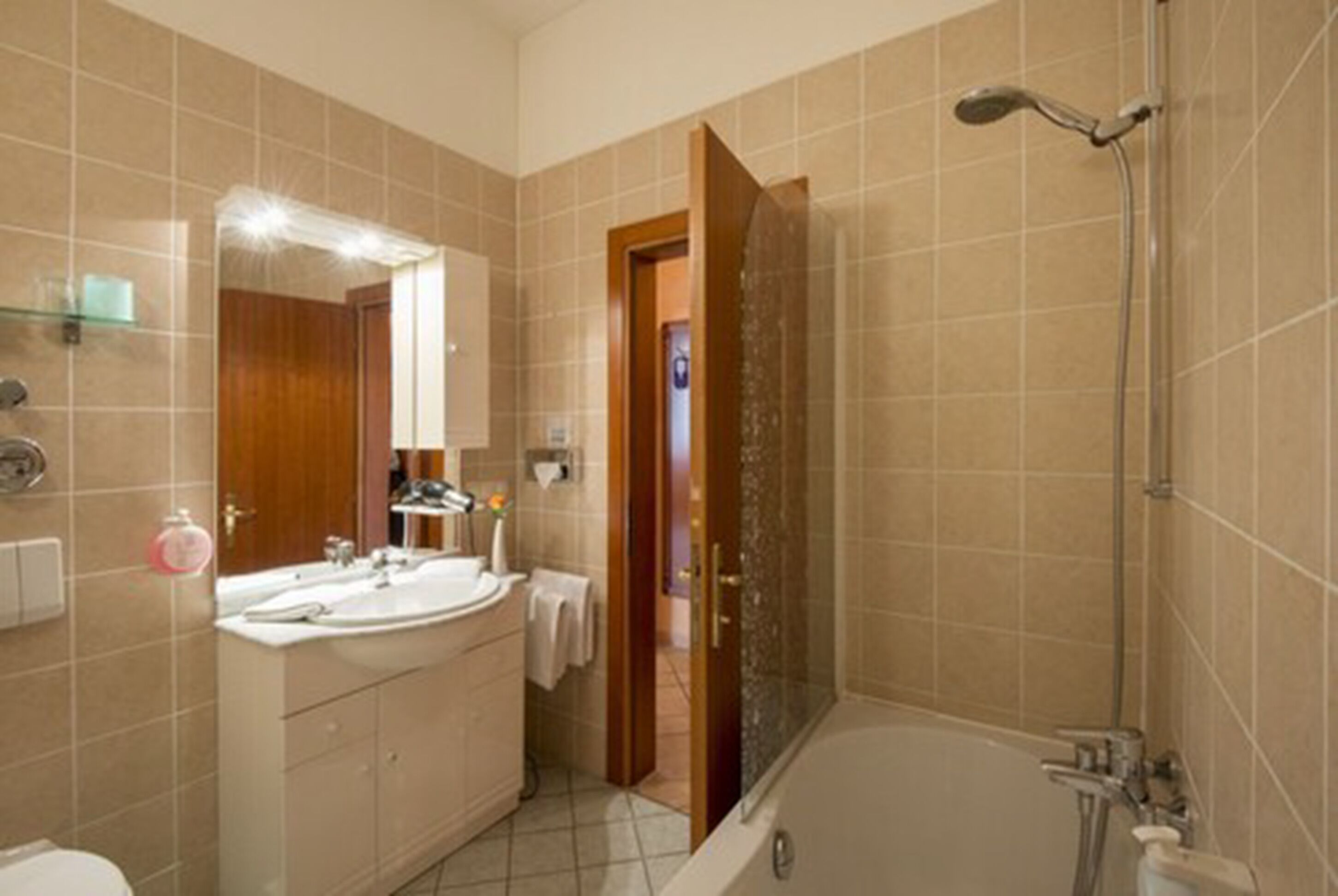 A bathroom with a bathtub, a shower, and a vanity with a mirror.