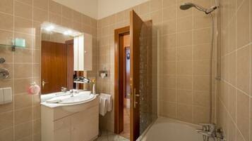 A bathroom with a bathtub, a shower, and a vanity with a mirror.