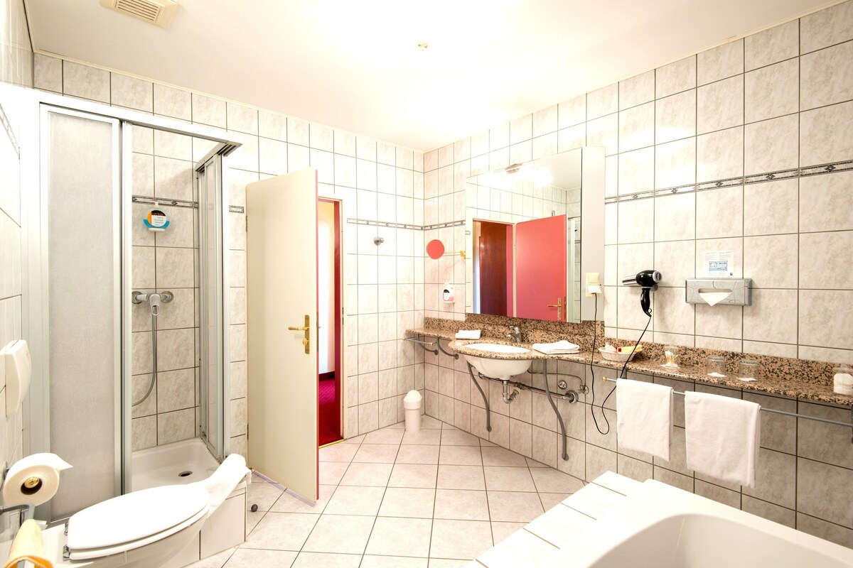 A modern bathroom with a shower, toilet, sink, and bathtub.