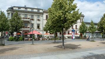 A hotel with outdoor seating, a cobblestone plaza, and trees.