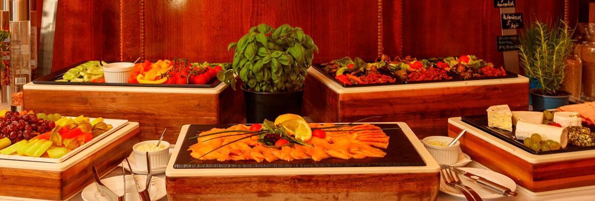 Ein Buffet mit verschiedenen Speisen und einer zentral platzierten Pflanze.