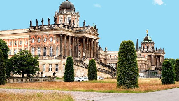 A large historic building with classical architecture, including columns and statues, and a prominent dome.