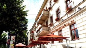 A hotel with outdoor seating, red umbrellas, and bicycles parked outside.