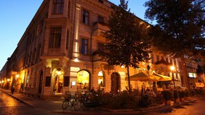 A historic building with a corner entrance, outdoor seating, and a bicycle parked in front.