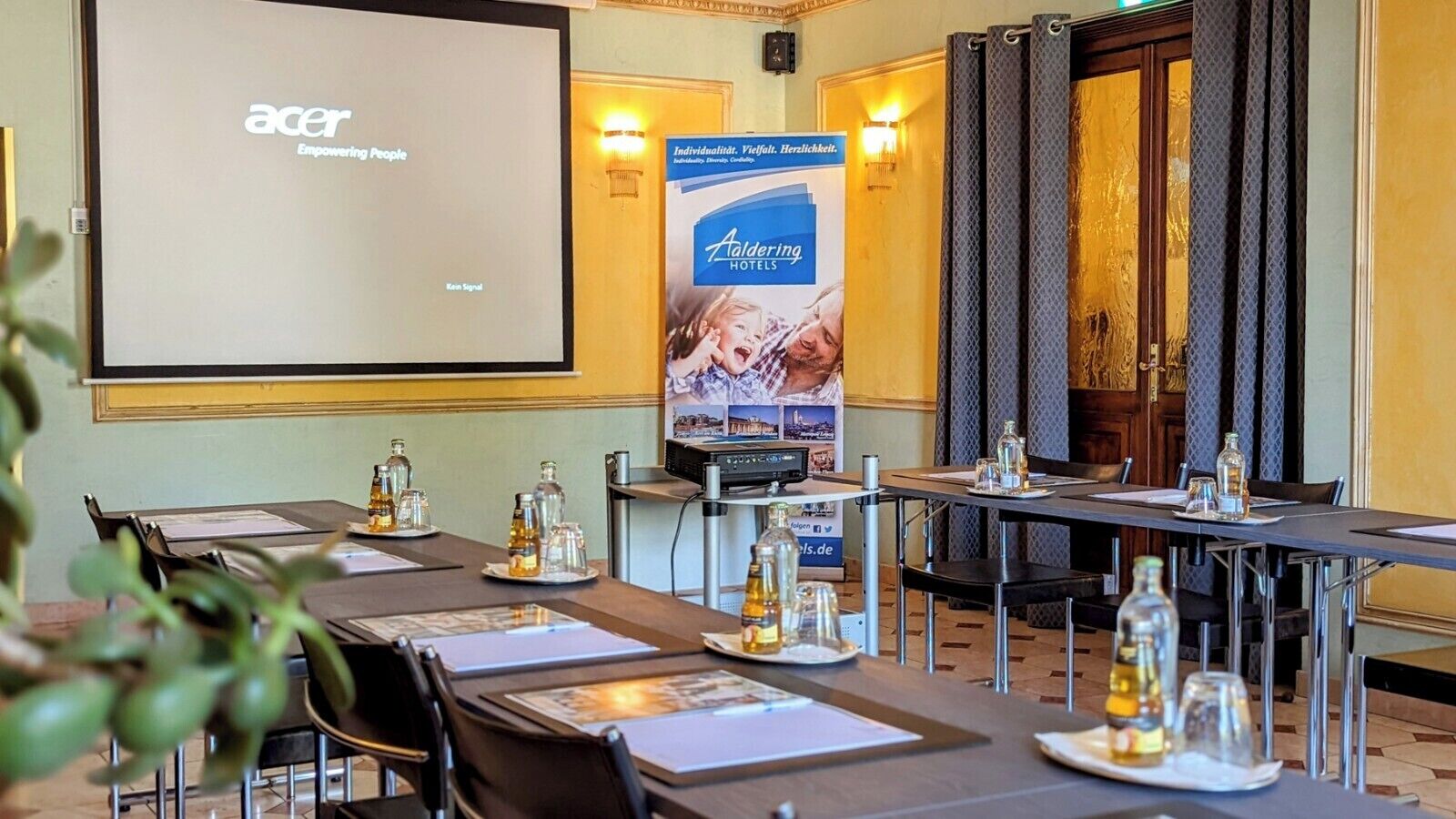 A conference room with tables set for meetings, a projector screen displaying 'Acer Empowering People', and a 'Taldering Hotels' banner.