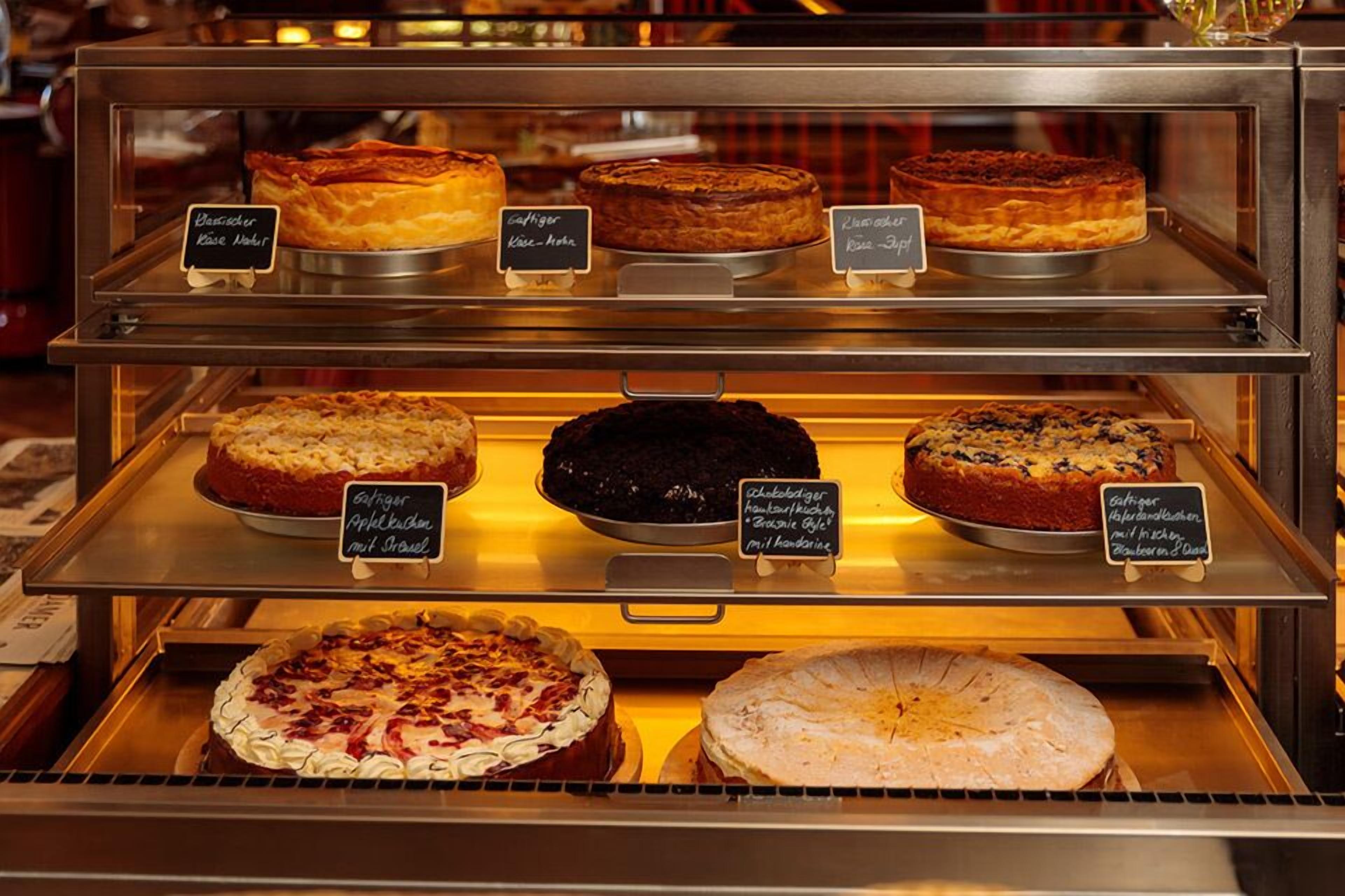A bakery display case with various cakes and pastries, each labeled with their names.