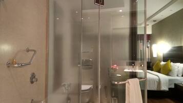 Un baño moderno con cabina de ducha de vidrio, inodoro a la vista y un perchero para toallas.