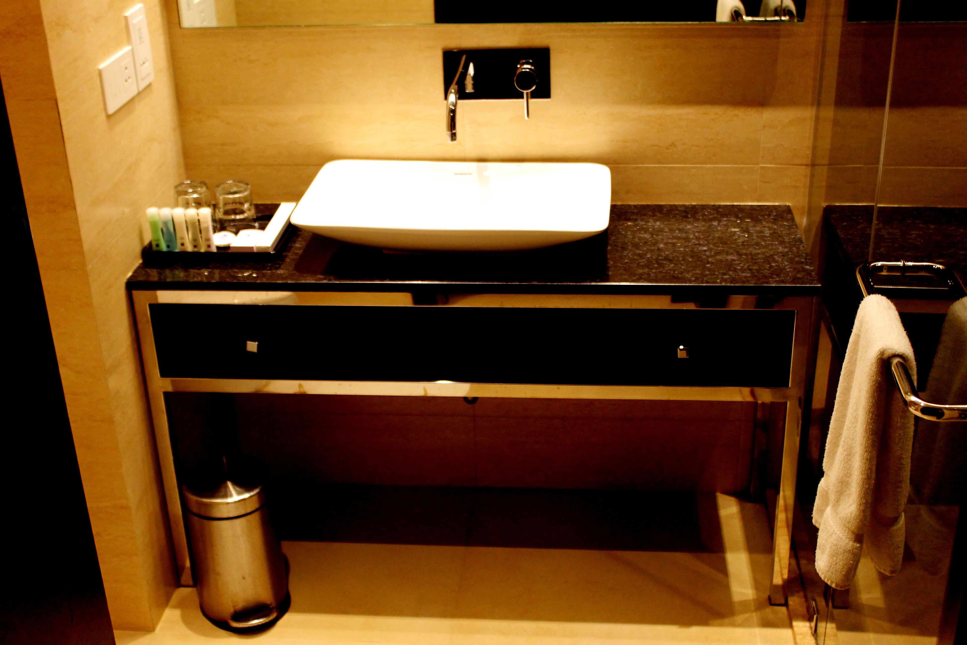 Une salle de bain avec un lavabo blanc, un plan de toilette foncé et un porte-serviettes.