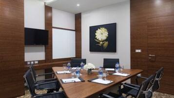 A conference room with a long table, black chairs, water bottles, and a flower centerpiece.