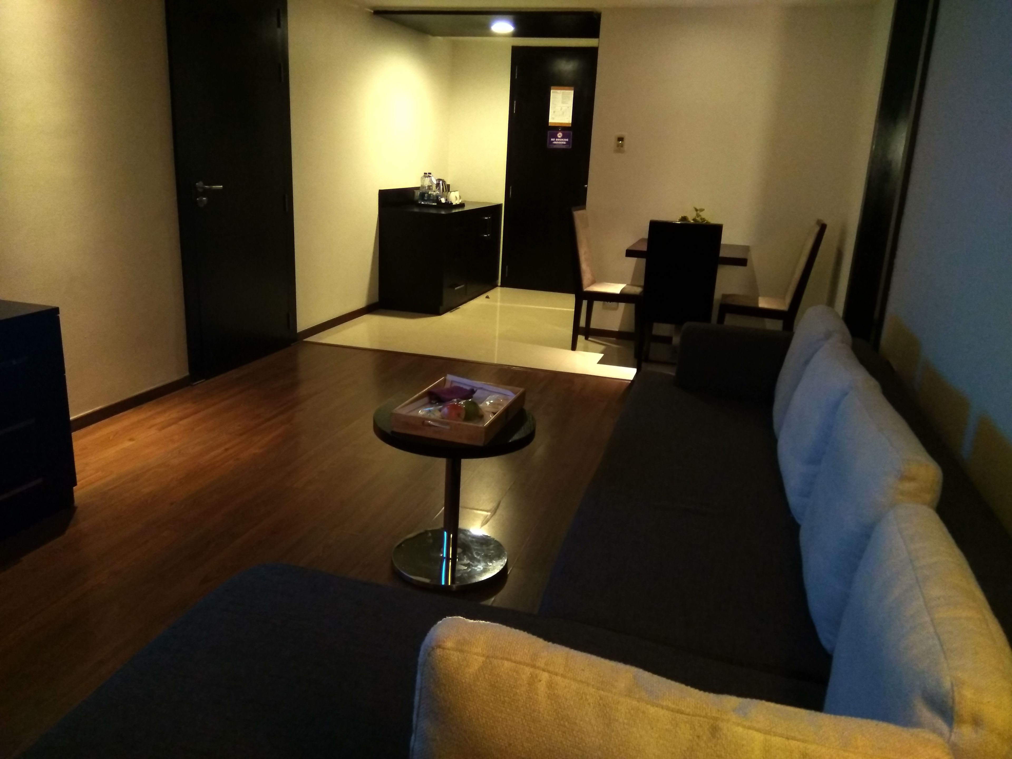 A modern living room with a dark-colored sofa, a small round table with a tray, and a wooden floor.