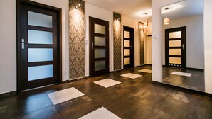 A hotel hallway with dark wooden doors, patterned wallpaper, and a tiled floor. - Hamilton Suites - Atlantis Apartments (Krakow)