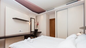 A hotel room with a bed, a desk, a mirror, and a wardrobe. - Hamilton Suites - Atlantis Apartments (Krakow)