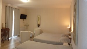 Ein Hotelzimmer mit zwei Betten, einem Schreibtisch, einem Stuhl, einem Fernseher und einem Spiegel.