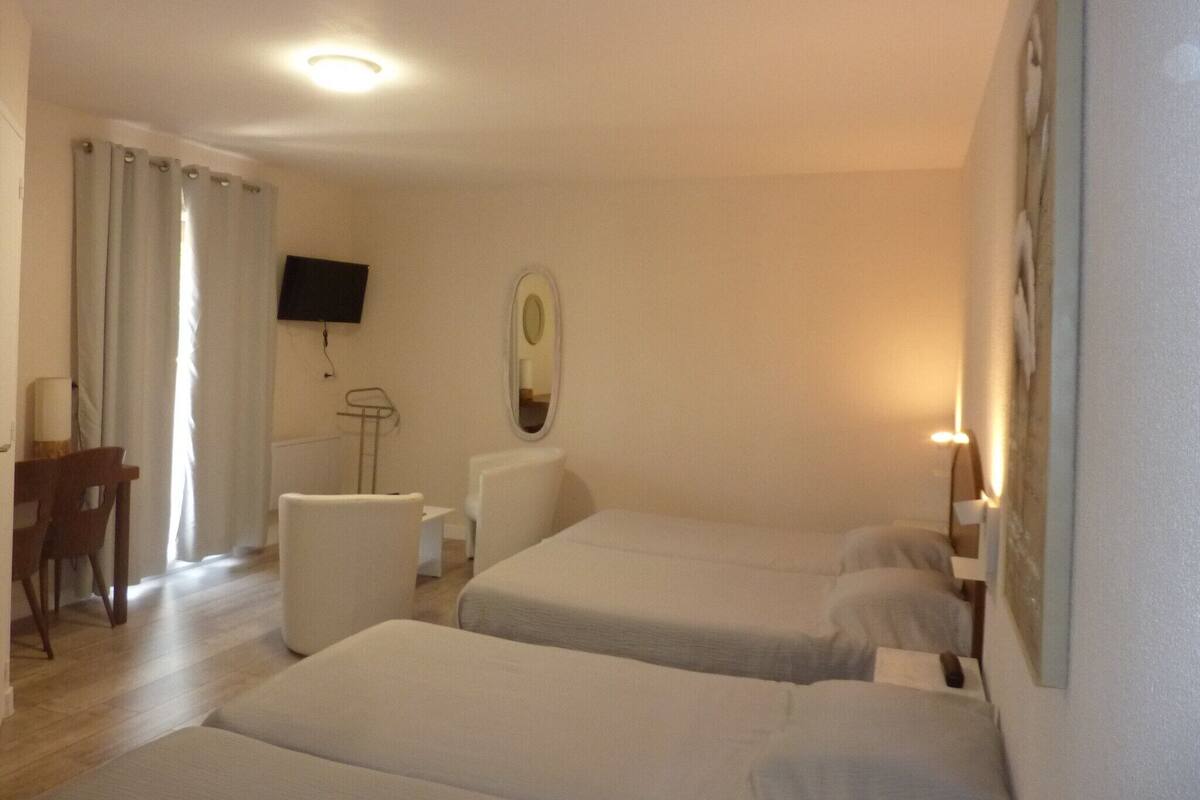 Hotellihuone, jossa on kaksi sänkyä, työpöytä, tuoli, televisio ja peili.