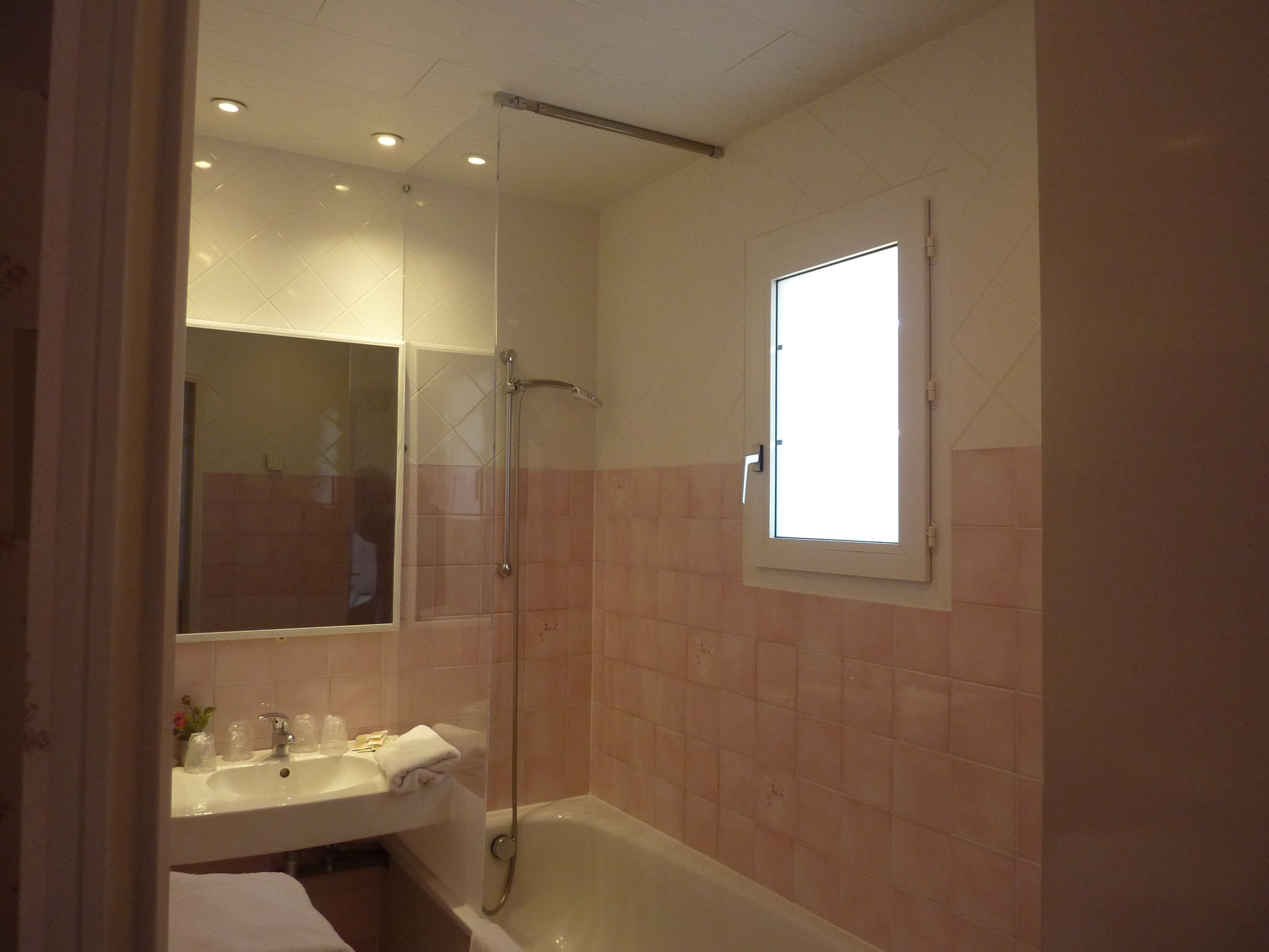 A bathroom with a sink, mirror, and shower.