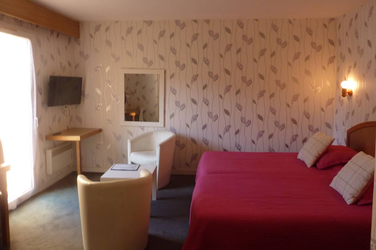 Hotellihuone, jossa on sänky, työpöytä, tuoli, televisio ja ikkuna.