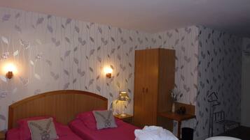 A hotel room with two beds, a wooden wardrobe, a desk, and a chair.