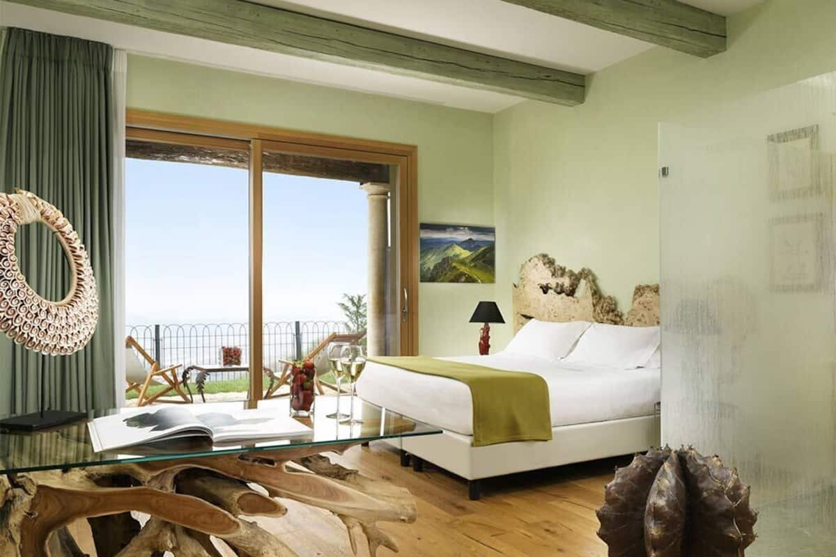 Un dormitorio con cama, una mesita de vidrio y vistas al exterior.