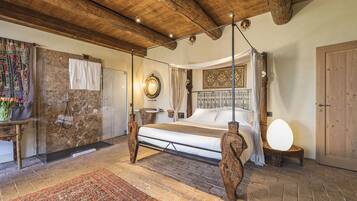 Una camera da letto con un letto grande, cabina doccia in vetro, soffitto in legno e arredamento in stile rustico.