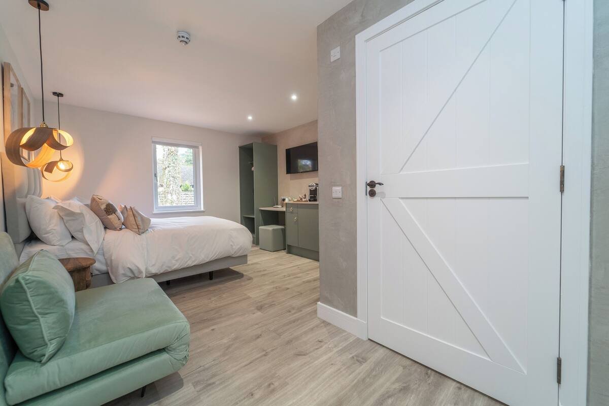 A bedroom with a bed, a green sofa, a TV, and a wardrobe.