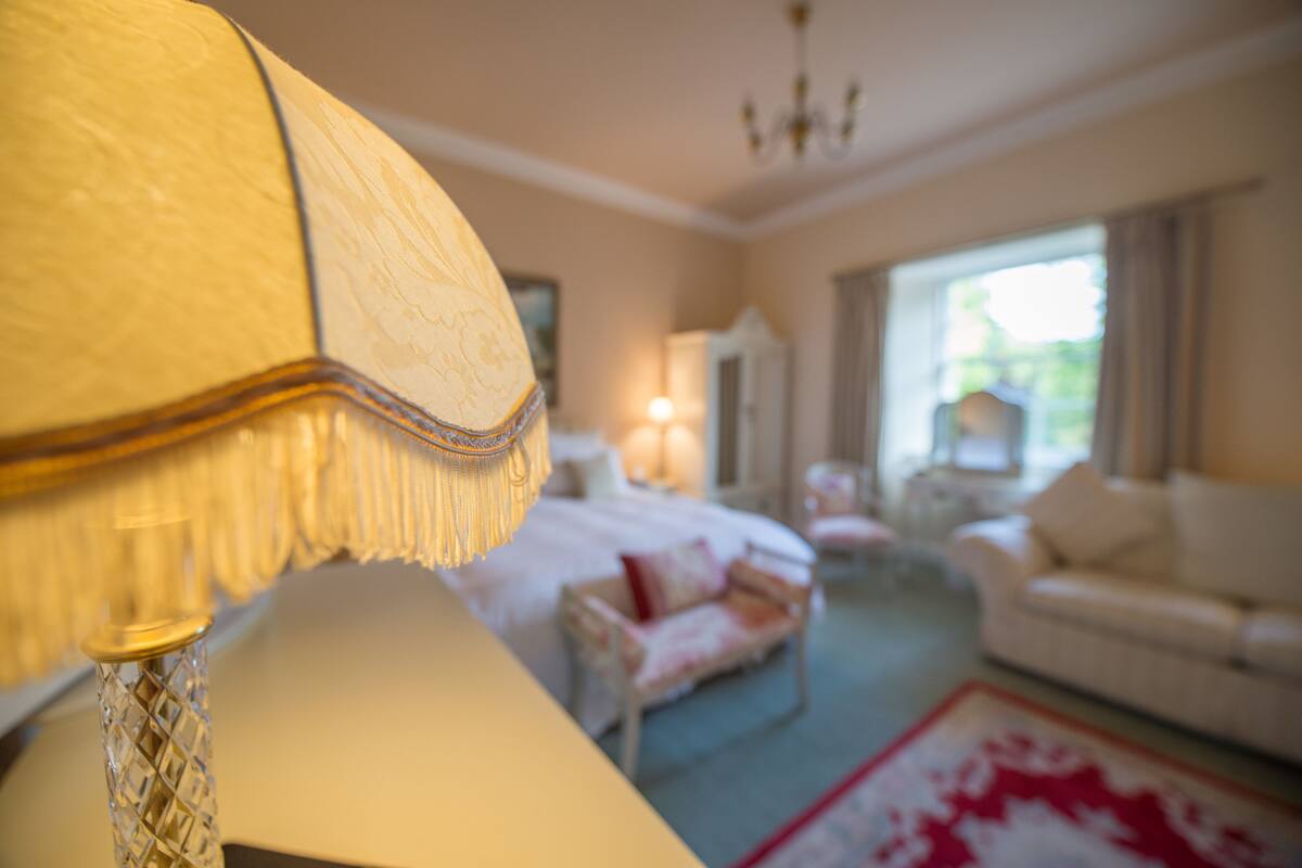 A room with a bed, a white sofa, and a chandelier.