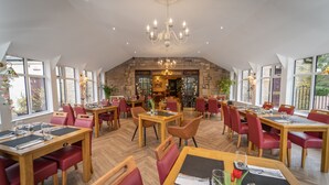 A spacious dining area with multiple tables and chairs, a chandelier, and large windows. - Bankton House Hotel (Livingston)