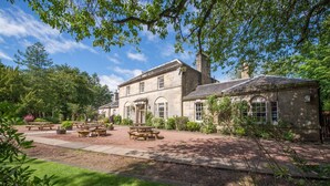 A historic stone building with a garden patio, picnic tables, and a well-maintained lawn. - Bankton House Hotel (Livingston)