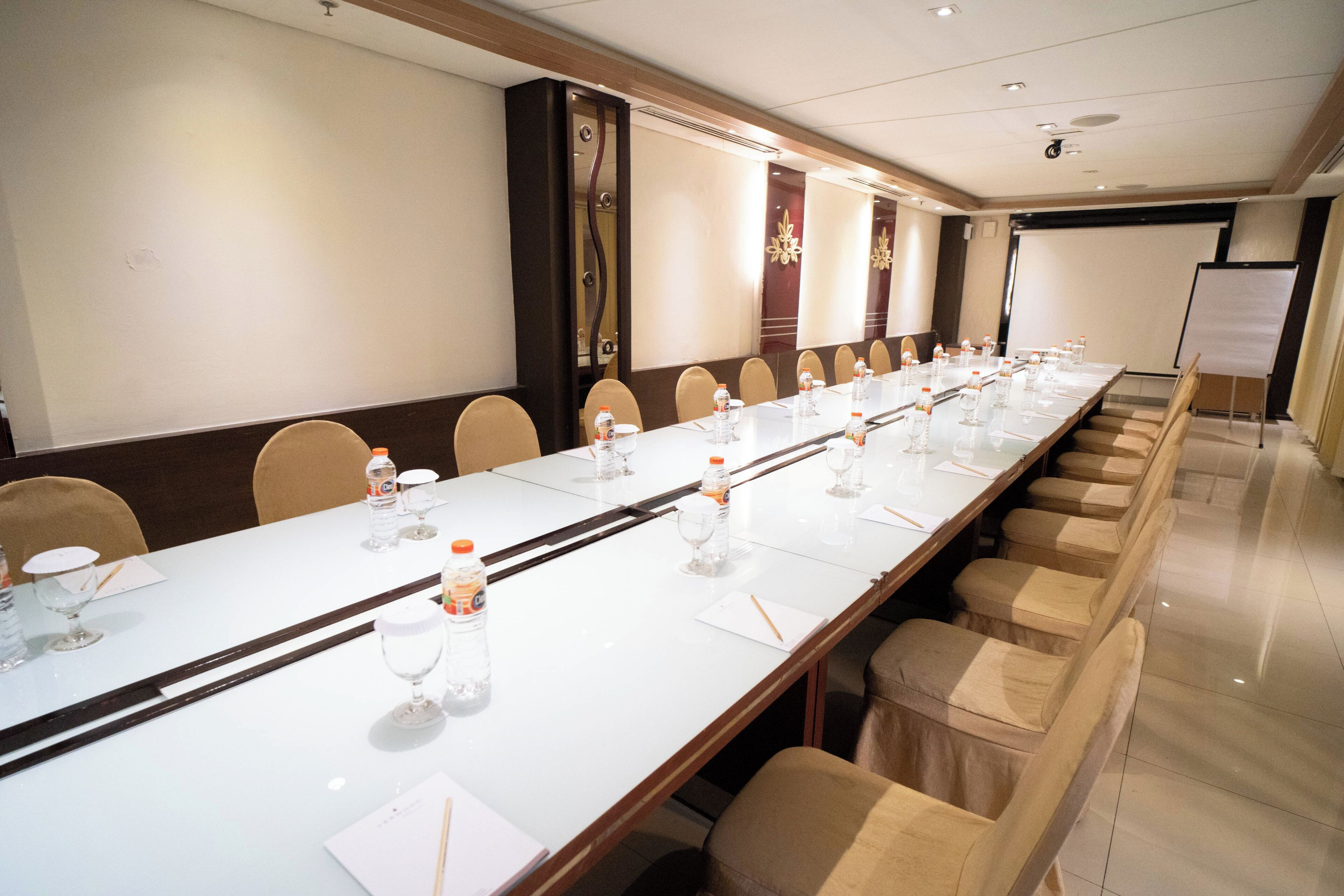 A conference room with a long table, chairs, water bottles, and a whiteboard.